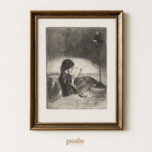 Op de afbeelding: Een ingelijste zwart-wit ets toont een persoon die bij lamplicht leest. Het kunstwerk, in een goudkleurige lijst, toont een zittende figuur die een boek leest, met een tafel, een lamp en een kopje. De stijl doet denken aan vintage illustraties.