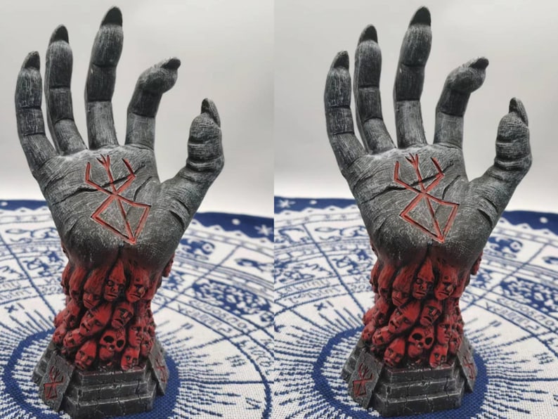 May include: A gray hand sculpture with a red symbol on the palm. The hand is holding a base filled with red faces.