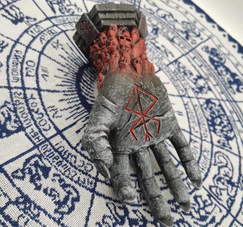 May include: A gray hand sculpture with a red symbol on the palm. The hand is covered in small, red, skull-like figures.
