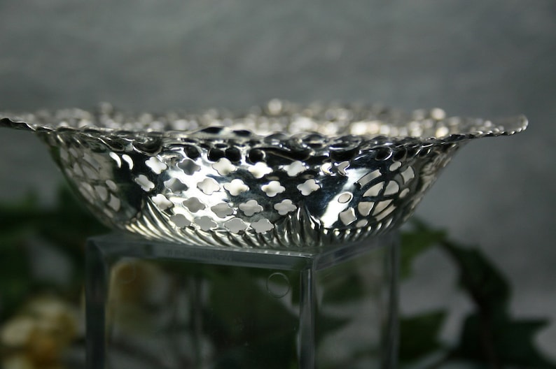 Puede incluir: Un cuenco de plata calado con un dise&ntilde;o delicado y de encaje. El cuenco est&aacute; hecho de metal y tiene un acabado brillante.