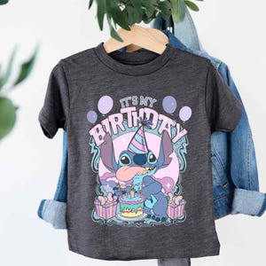 a t - shirt hanging on a clothes rack next to a plant