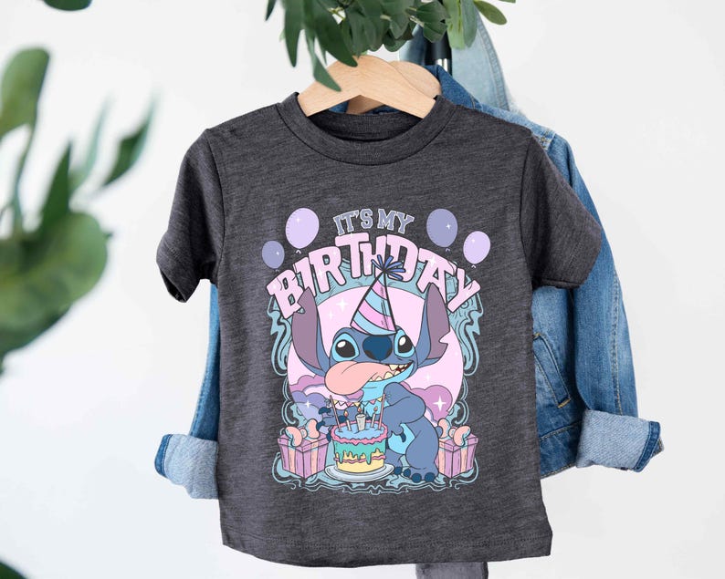 a t - shirt hanging on a clothes rack next to a plant