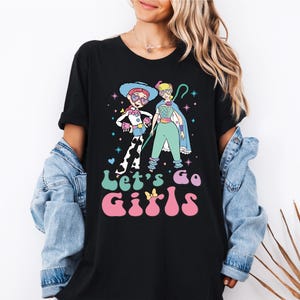 a woman wearing a black t - shirt with a cartoon character on it
