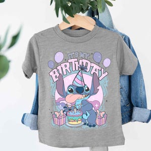 a t - shirt hanging on a clothes rack next to a plant