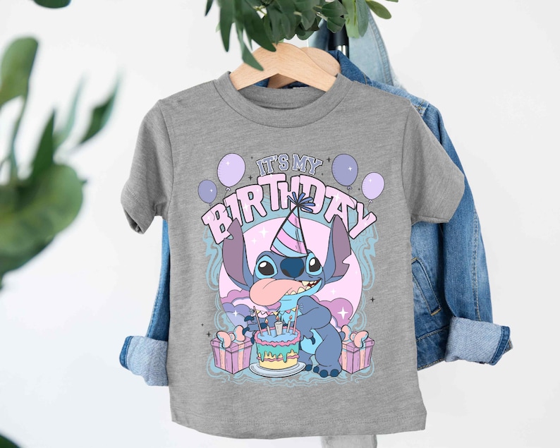 a t - shirt hanging on a clothes rack next to a plant