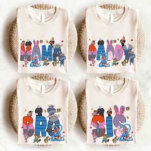 four white t-shirts with colorful text and illustrations, each featuring a different character or phrase.