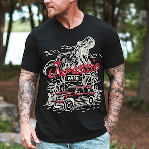 a man wearing a black t - shirt with a dinosaur on it