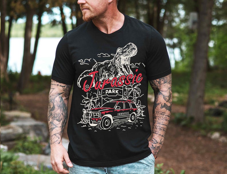 a man wearing a black t - shirt with a dinosaur on it