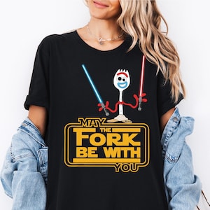 May include: Black t-shirt featuring a cartoon character holding two lightsabers. The text "May the Fork Be With You" is printed on the shirt.