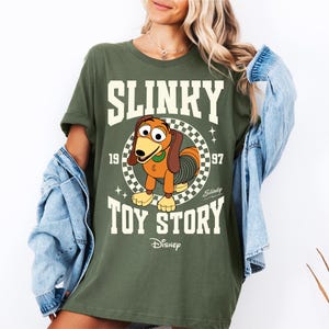a woman wearing a shirt that says slinky is the toy story
