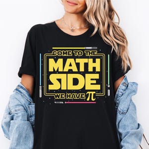 Op de afbeelding: Zwart T-shirt met een gele afbeelding met de tekst "Come to the Math Side We Have Pi" met lichtzwaardafbeeldingen.