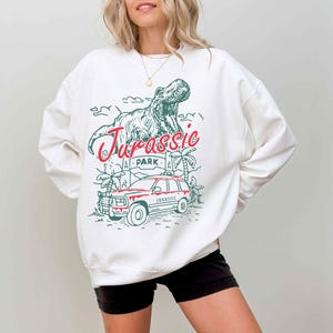 a woman wearing a white sweatshirt with a dinosaur on it