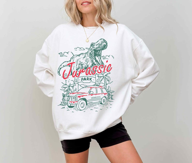 a woman wearing a white sweatshirt with a dinosaur on it