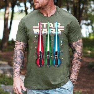 a man wearing a star wars shirt with two lightsabes on it