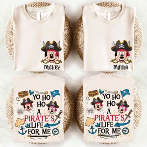May include: Two white t-shirts with a pirate Mickey Mouse design. One shirt has Mickey Mouse with the text "Mickey" and the other has Minnie Mouse with the text "Minnie". The other two shirts have a pirate Mickey Mouse design with the text "Yo Ho Ho A Pirate's Life For Me".