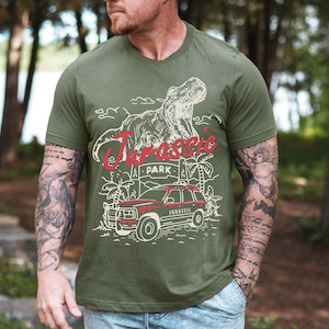 a man wearing a green t - shirt with a picture of a dinosaur on it