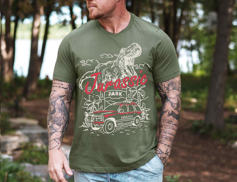 a man wearing a green t - shirt with a picture of a dinosaur on it