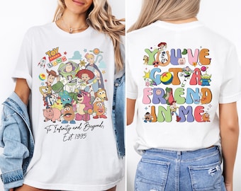 May include: White t-shirt with a colorful graphic of Toy Story characters on the front and the text "You've Gotta Friend in Me" on the back. The front graphic includes the text "Toy Story Land" and "To Infinity and Beyond, Est. 1995".