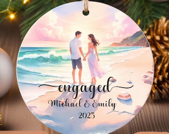 May include: Round ornament with a beach scene featuring a couple holding hands, with the word "engaged" and the names "Michael & Emily" and the year "2025". The ornament has a string for hanging.