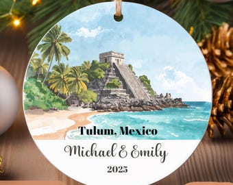 May include: Round ceramic ornament featuring a watercolor painting of Tulum, Mexico, with a pyramid and beach scene. Text includes "Tulum, Mexico," a name, and the year 2025. A jute string is attached for hanging.