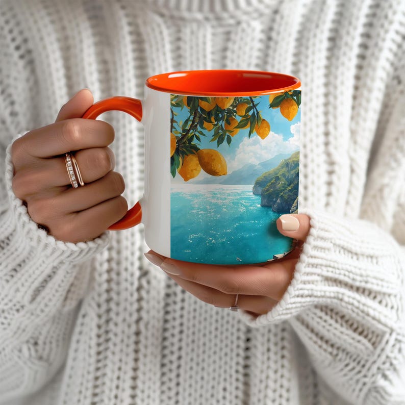Amalfi Coast mug with blue interior held by person wearing cozy sweater, seaside view artwork visible