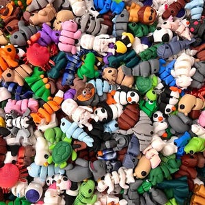 May include: A large collection of colourful, small, plastic figurines. The figurines are shaped like various animals, including turtles, penguins, and insects. The figurines are all different colours, including red, blue, green, yellow, and orange.