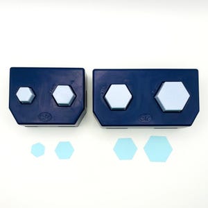 May include: Two dark blue paper punch tools with light blue hexagonal buttons. The left tool features 0.5 inch and 1 inch sizes, while the right tool features 1.5 inch and 2 inch sizes. Four light blue hexagonal paper cutouts are placed below.