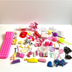 May include: A large collection of miniature plastic doll accessories including a pink lounge chair, a red cowboy hat, a pink rocking horse, various kitchen utensils, small containers, hangers, sports equipment, and colorful toy electronics.