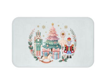 May include: A rectangular bath mat featuring a central illustration of a pink and green Christmas tree, a nutcracker, a ballerina, a mouse king, a rocking horse, and gift boxes, all surrounded by a wreath of holly leaves and berries.