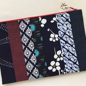 May include: A blue and red patchwork zippered pouch with a variety of floral and geometric patterns.