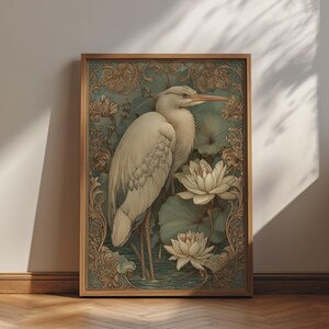 May include: A framed vertical wall art print featuring a white heron standing among large white lotus flowers and green lily pads. The artwork is surrounded by an intricate, ornate, light brown border with swirling floral patterns and scrollwork.