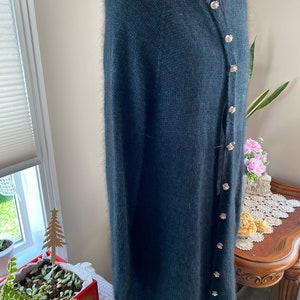 May include: A dark blue fuzzy cardigan with a button closure. The cardigan has a round neckline and long sleeves.