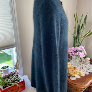 May include: A long-sleeved, dark blue cardigan sweater with a fuzzy texture. The sweater has a button closure and a ribbed hem.