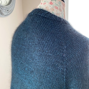 May include: A dark blue knitted sweater with a subtle ombre effect, featuring a soft, fuzzy texture.