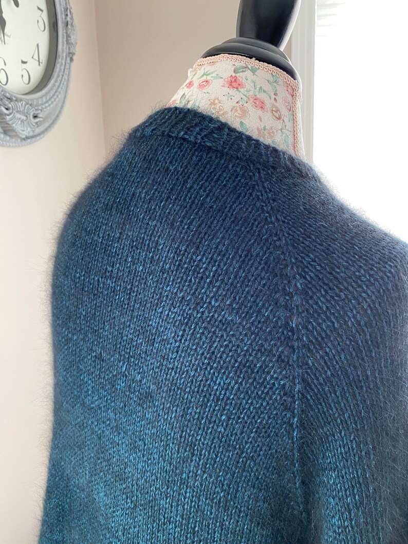 May include: A dark blue knitted sweater with a subtle ombre effect, featuring a soft, fuzzy texture.