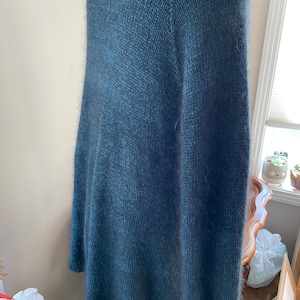 May include: A dark blue fuzzy knit cardigan with a long, loose fit.