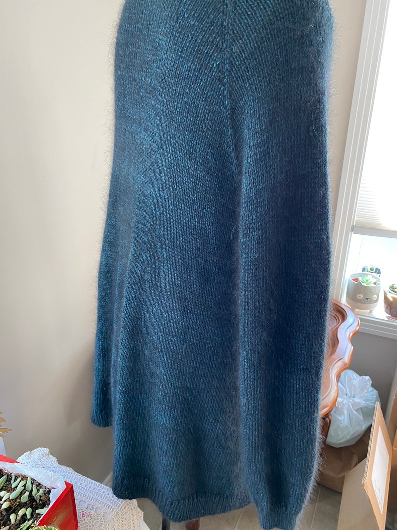 May include: A dark blue fuzzy knit cardigan with a long, loose fit.