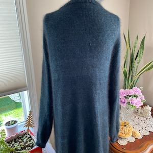 May include: A dark teal blue fuzzy knit cardigan sweater with long sleeves and a v-neck.