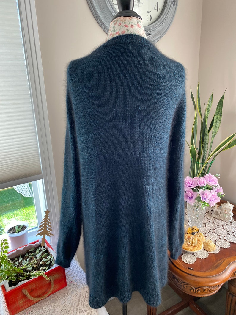 May include: A dark teal blue fuzzy knit cardigan sweater with long sleeves and a v-neck.