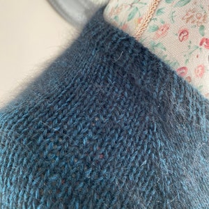 May include: A dark blue knitted sweater with a fuzzy texture.