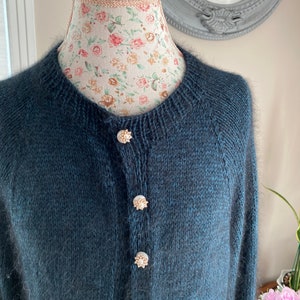 May include: A dark blue cardigan with a fuzzy texture and pearl buttons.