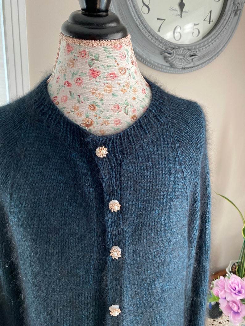 May include: A dark blue cardigan with a fuzzy texture and pearl buttons.