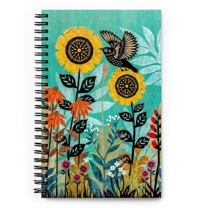 May include: A teal blue background with a black bird flying over a field of sunflowers and other flowers. The sunflowers have black centers and yellow petals. The other flowers are red, orange, and white.