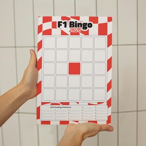 Può includere: Un tabellone rettangolare del gioco F1 Bingo 2026 con un design a scacchi rosso e bianco. Il tabellone presenta una griglia di quadrati vuoti e una sezione per le previsioni della classifica. Il tabellone è tenuto da due mani.
