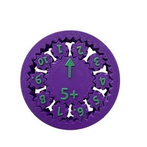 May include: Purple plastic gear with green numbers 1 through 10, 5+, and L.9. The gear has an arrow pointing upwards.