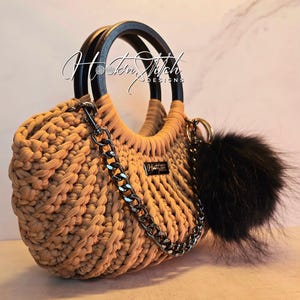 Bolso de mano con pompón de crochet con asa superior negra y palito de canela