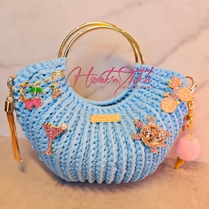 Bolso de mano con asa superior de crochet y dijes en oro rosa y azul