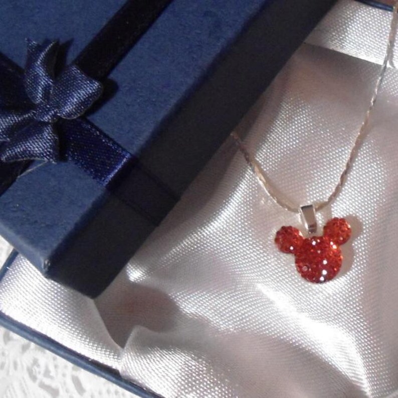 May include: A red crystal Mickey Mouse pendant necklace in a blue gift box with a white satin lining.