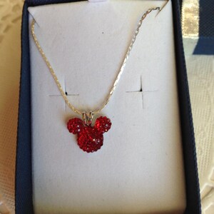 May include: A silver chain necklace with a red rhinestone Mickey Mouse pendant.