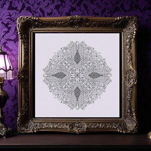Puede incluir: Un diseño de mandala en blanco y negro en un marco dorado adornado. El mandala es intrincado y detallado, con un patrón circular de flores y hojas.